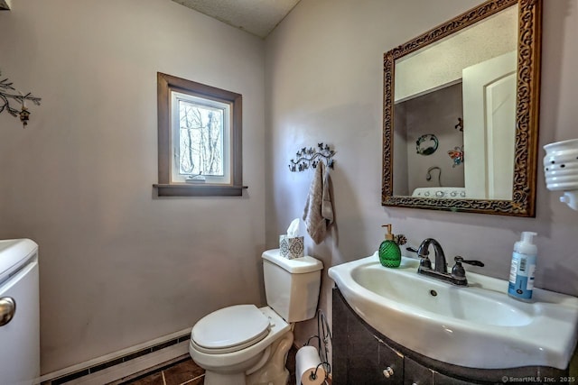 bathroom with a baseboard radiator, sink, tile patterned flooring, toilet, and a textured ceiling