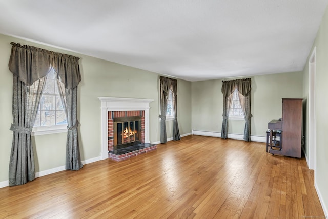 unfurnished living room featuring hardwood / wood-style flooring and a brick fireplace