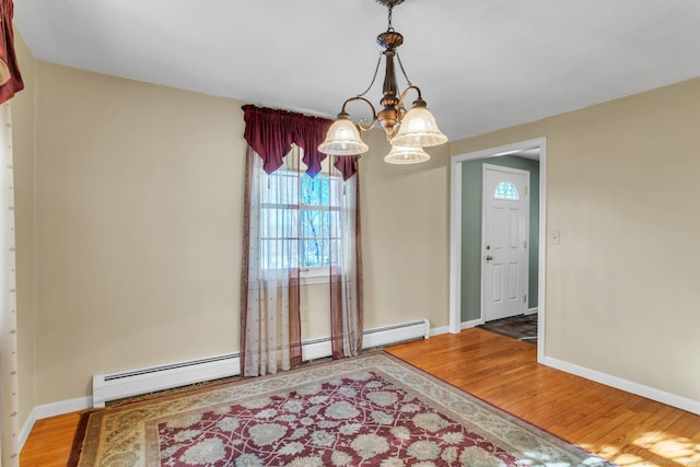 dining space featuring an inviting chandelier, baseboard heating, and hardwood / wood-style floors