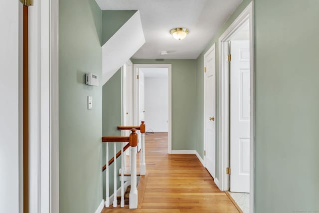 corridor with light hardwood / wood-style floors and a textured ceiling