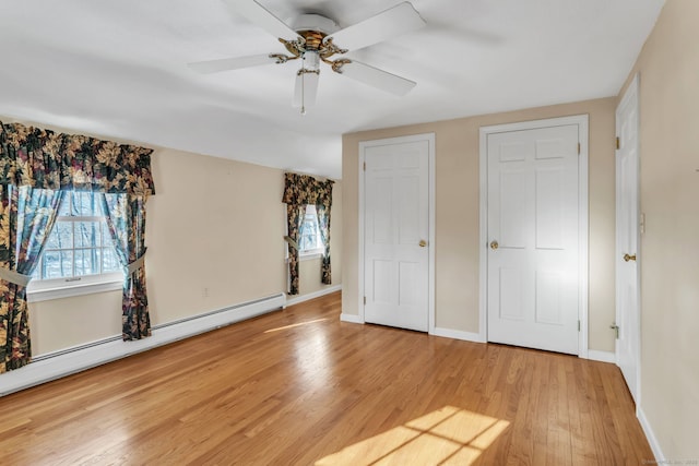 unfurnished bedroom with a baseboard heating unit, hardwood / wood-style flooring, and ceiling fan