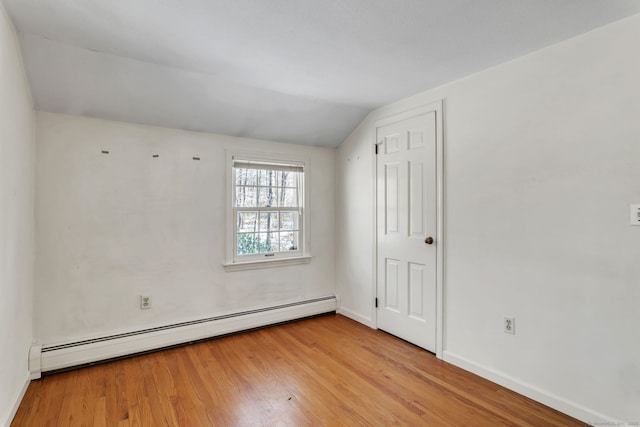 empty room with light hardwood / wood-style floors, vaulted ceiling, and a baseboard heating unit