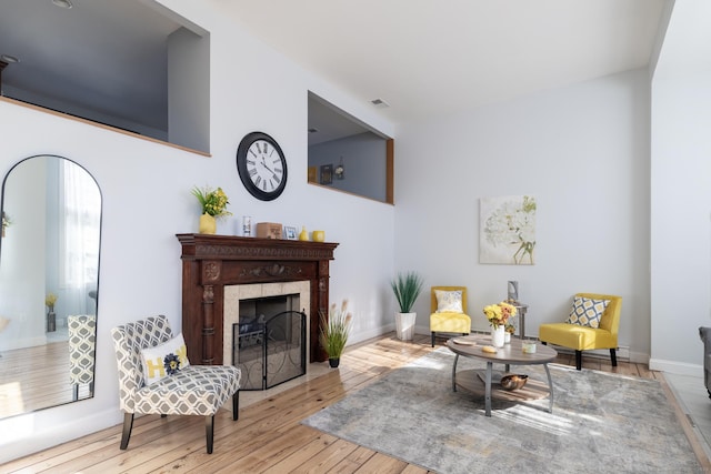 sitting room with a tile fireplace and light wood-type flooring