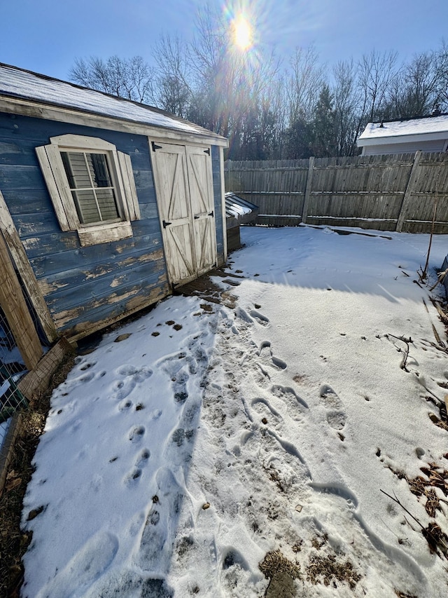 snowy yard featuring a storage unit