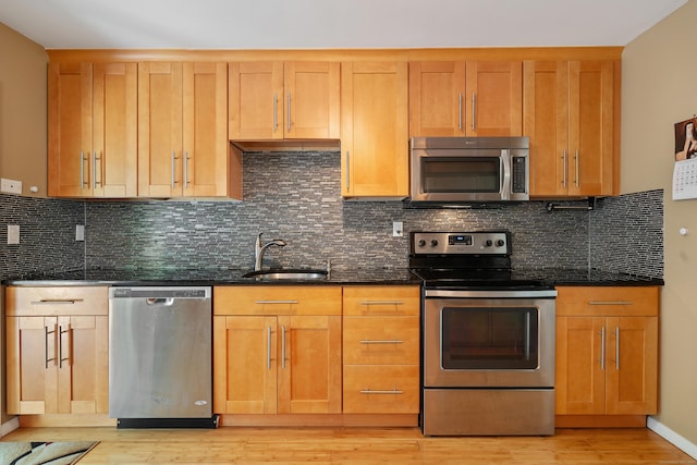 kitchen featuring appliances with stainless steel finishes, sink, dark stone countertops, and decorative backsplash