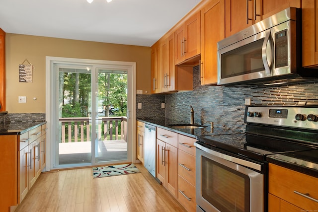 kitchen with stainless steel appliances, sink, light hardwood / wood-style flooring, and decorative backsplash