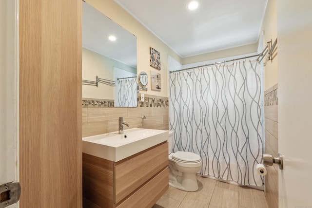 bathroom with a shower with curtain, vanity, toilet, and tile walls