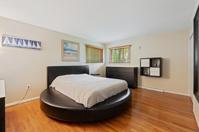 bedroom with a baseboard heating unit and wood-type flooring