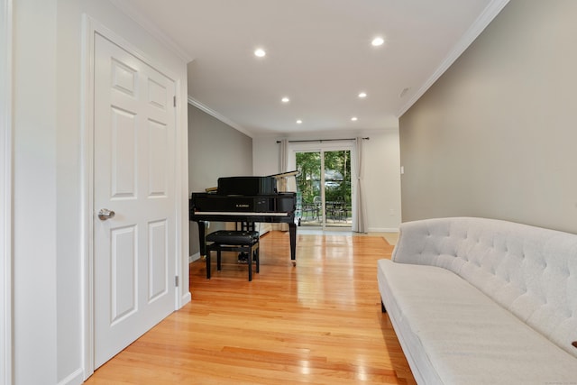 living area with crown molding and light hardwood / wood-style flooring