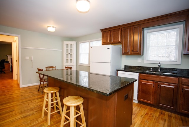 kitchen with sink, white appliances, light hardwood / wood-style flooring, and a kitchen island