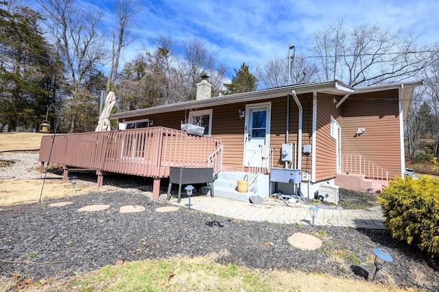 back of house featuring a deck and a chimney