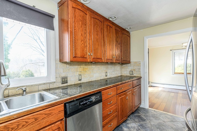 kitchen featuring a healthy amount of sunlight, tile countertops, baseboard heating, appliances with stainless steel finishes, and brown cabinetry