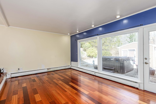 empty room with crown molding, wood finished floors, and a baseboard radiator