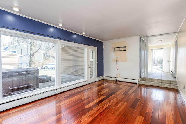 empty room with ornamental molding, wood finished floors, and a baseboard radiator