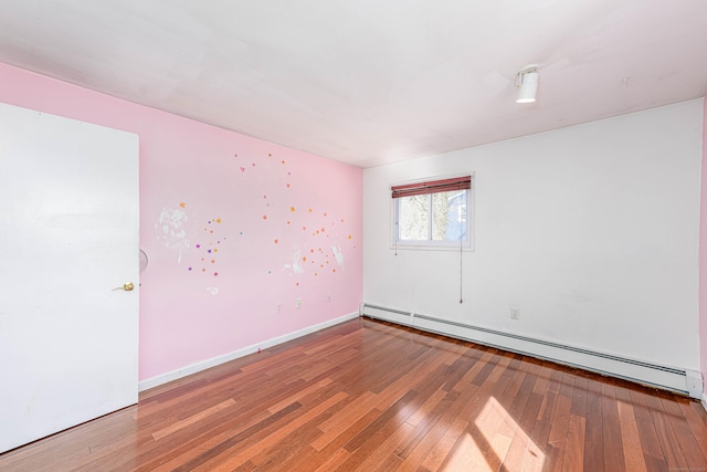 spare room with a baseboard heating unit, baseboards, and hardwood / wood-style floors