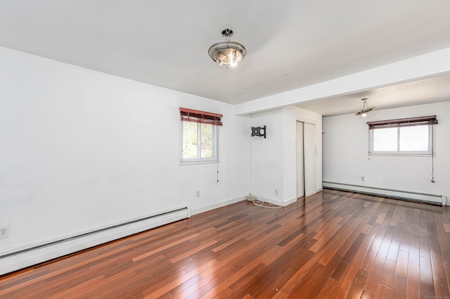 spare room featuring a baseboard heating unit, plenty of natural light, and hardwood / wood-style floors