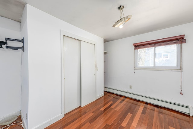 unfurnished bedroom with a baseboard radiator, a closet, and wood finished floors