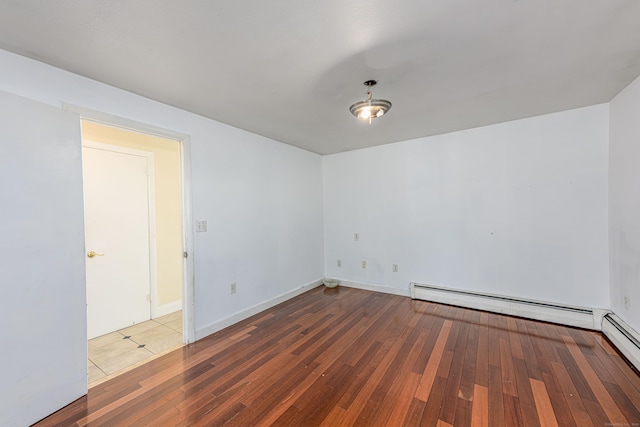 empty room featuring a baseboard radiator, baseboards, and hardwood / wood-style flooring