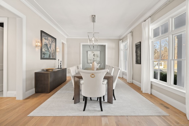 dining area with crown molding and light hardwood / wood-style flooring