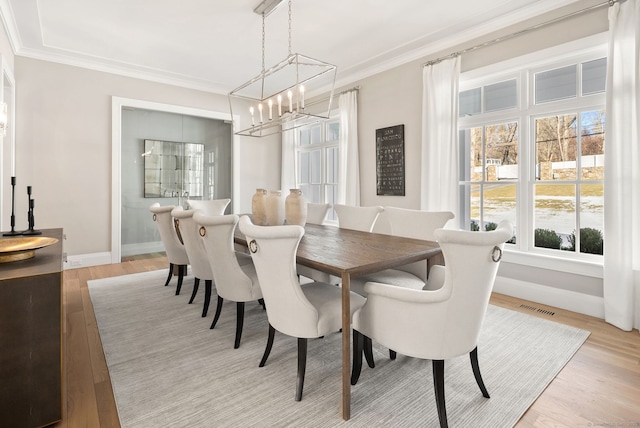 dining room with crown molding and light hardwood / wood-style floors