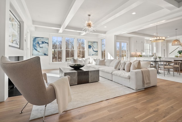 living room with a notable chandelier, beam ceiling, and light hardwood / wood-style flooring