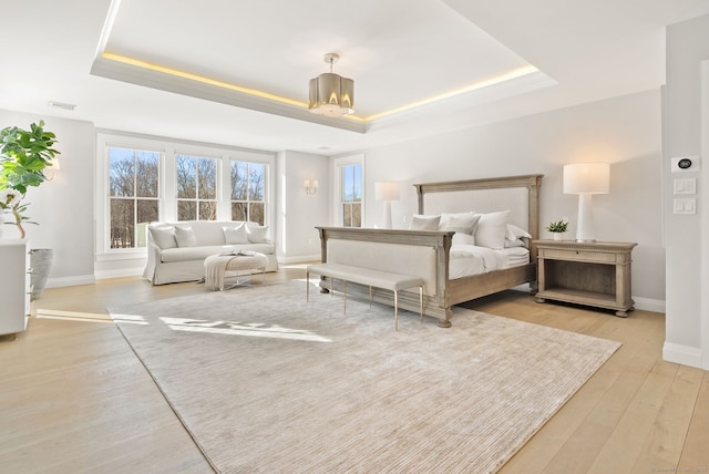 bedroom with a tray ceiling, light hardwood / wood-style floors, and a notable chandelier