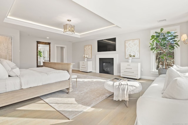 bedroom featuring hardwood / wood-style floors, a notable chandelier, and a tray ceiling