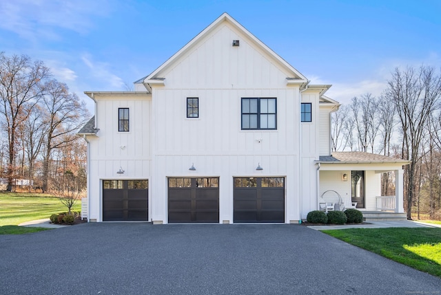 modern inspired farmhouse with a garage, a porch, and a front lawn