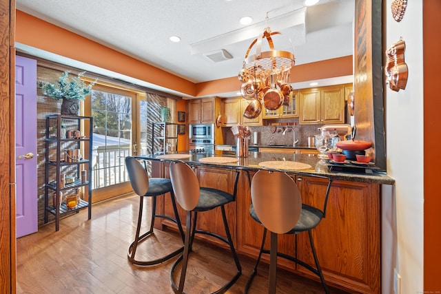 kitchen with a breakfast bar, tasteful backsplash, sink, dark stone countertops, and stainless steel appliances