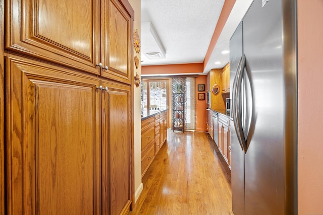 kitchen featuring light hardwood / wood-style flooring, stainless steel refrigerator, a textured ceiling, and stone countertops