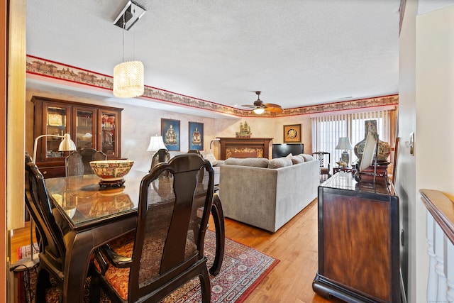 dining room with ceiling fan, light hardwood / wood-style flooring, and a textured ceiling