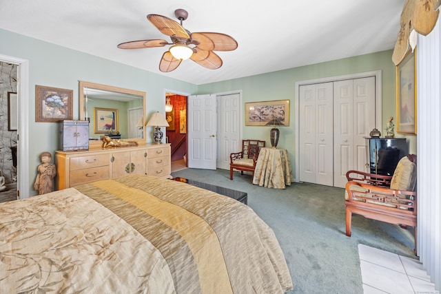 bedroom with ceiling fan, light colored carpet, and two closets