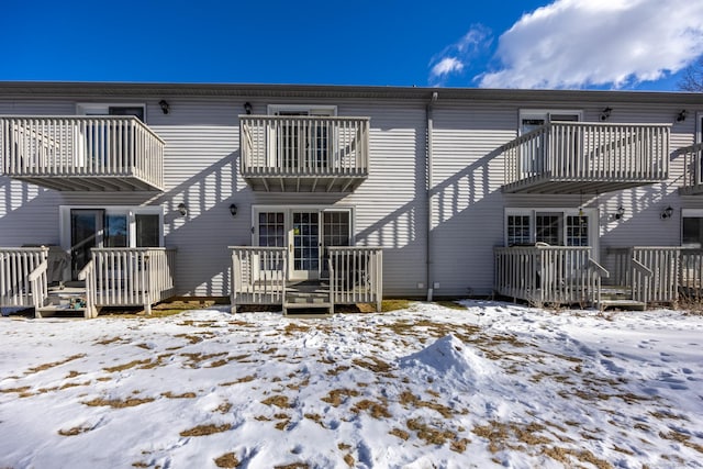 snow covered house with a wooden deck and a balcony