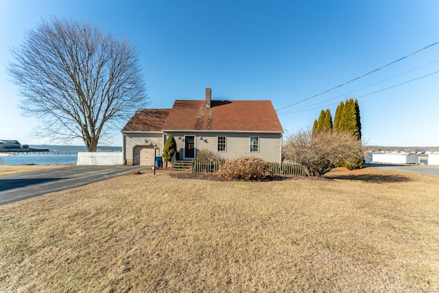 view of front of property featuring a garage, a front lawn, and a water view