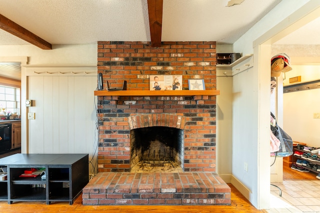 living room with beamed ceiling, hardwood / wood-style flooring, a fireplace, and a textured ceiling