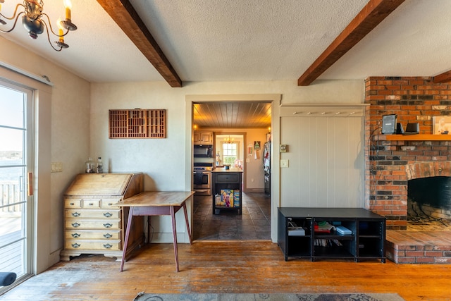 kitchen with beamed ceiling, a brick fireplace, a textured ceiling, and hardwood / wood-style flooring