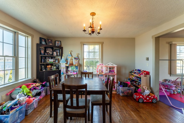 dining space with hardwood / wood-style floors, a notable chandelier, and a textured ceiling