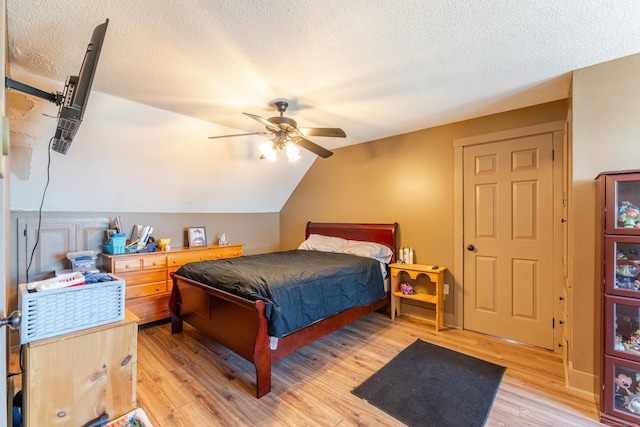 bedroom featuring lofted ceiling, ceiling fan, light hardwood / wood-style flooring, and a textured ceiling