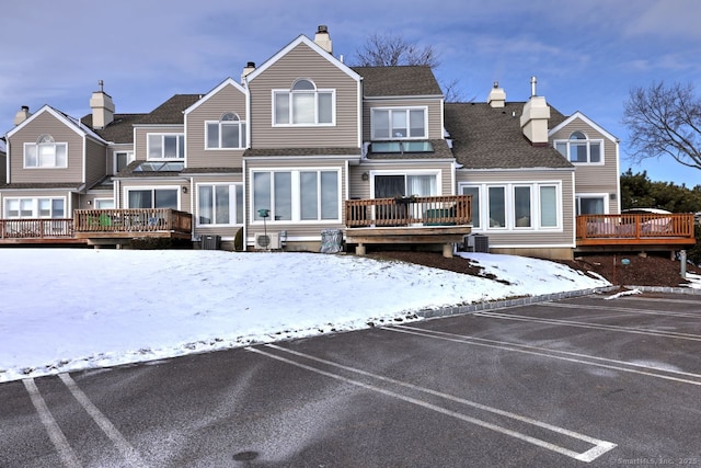 snow covered rear of property featuring a wooden deck and cooling unit