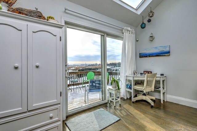 doorway featuring hardwood / wood-style flooring and vaulted ceiling with skylight