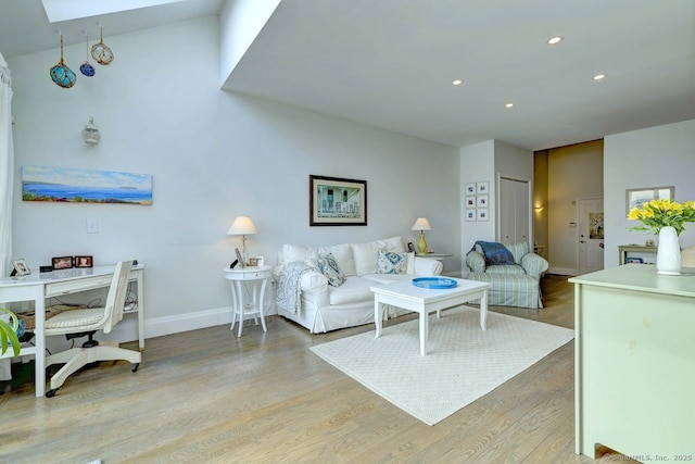 living room with a skylight and light hardwood / wood-style floors