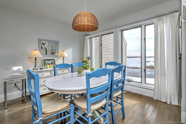 dining space with a water view and dark hardwood / wood-style floors