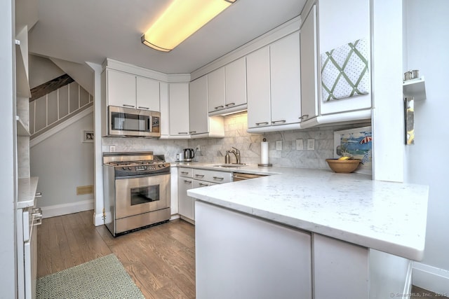 kitchen featuring tasteful backsplash, white cabinets, kitchen peninsula, stainless steel appliances, and light wood-type flooring