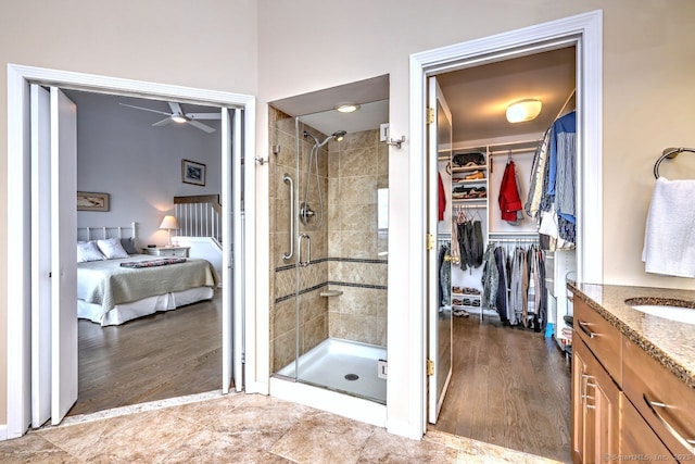 bathroom featuring ceiling fan, vanity, and a shower with door