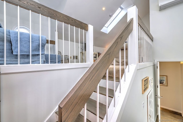 staircase with hardwood / wood-style flooring, a wall mounted air conditioner, and lofted ceiling with skylight