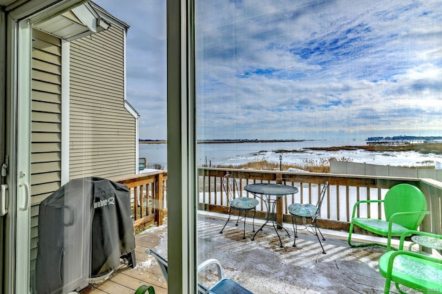 snow covered back of property featuring a deck with water view