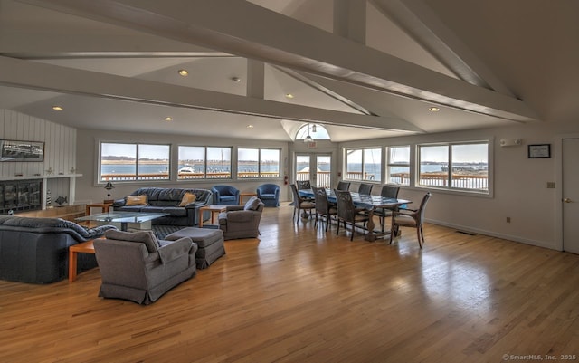 living room with a tiled fireplace, light hardwood / wood-style floors, and lofted ceiling with beams