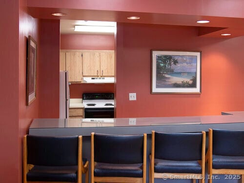 kitchen featuring light brown cabinetry, range with electric stovetop, and fridge