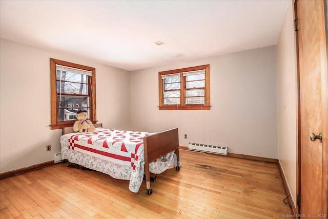 bedroom with multiple windows, hardwood / wood-style flooring, and baseboard heating