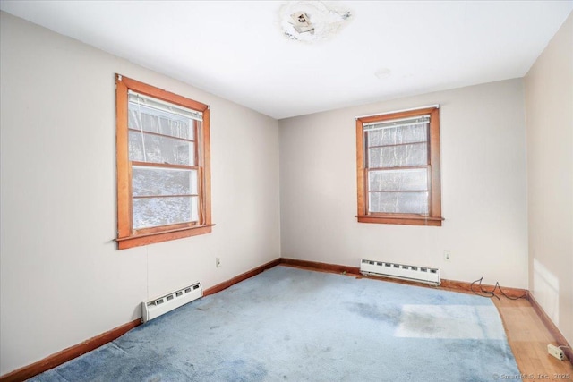 unfurnished room with light colored carpet and a baseboard heating unit